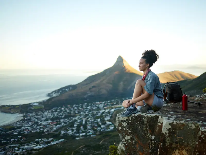 Woman enjoying a hiking trip with a clear mountain and city view